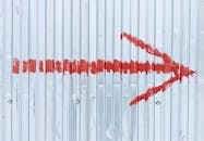 A vibrant red arrow painted on a corrugated metal wall directs attention to the right.