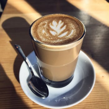 A beautiful cup of latte with artistic foam design in a cozy café, captured in natural daylight.